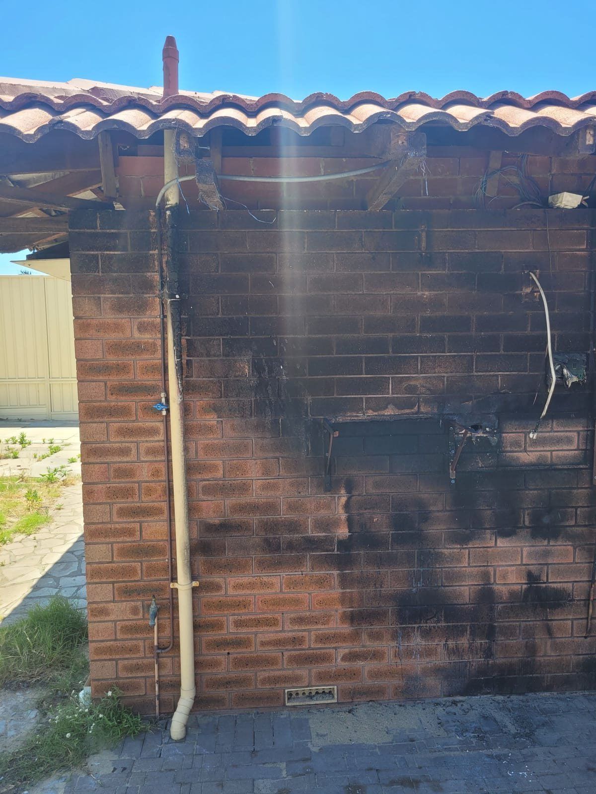 Brick exterior wall covered in heavy soot from fire damage